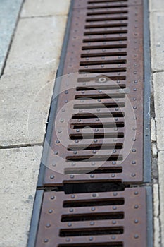 Rusty storm drain grate on side of road. Urban infrastructure, road protection from floods, heavy rains