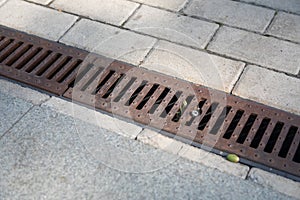Rusty storm drain grate on side of road. Urban infrastructure, road protection from floods, heavy rains