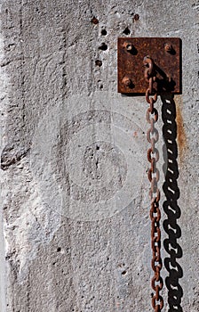 Rusty strong chain hanging along the wall