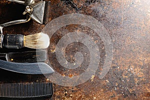 On a rusty surface are old hairdresser tools. manual clipper, comb, razor, shaving brush. rustic. horizontal. top view. flat ley.