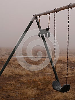 Rusty swingset in the fog photo