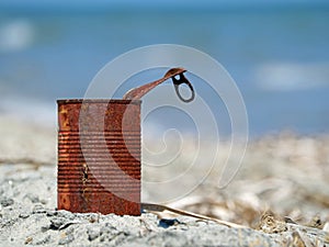 Rusty tin can on the beach with blue sea