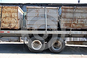 Rusty trash dumpsters on flatbed trailer