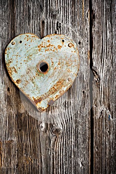 Rusty trim on keyhole as heart on old wooden door. Vertical shot