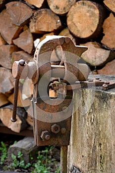 A rusty vice located outside on a stump is used to grip objects for work, also to sharpen a hand scythe.