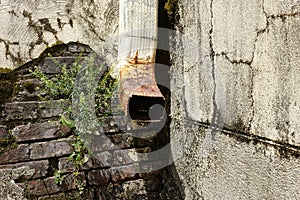 Rusty Water Down Spout on an Eroding Exterior Wall