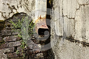 Rusty Water Down Spout on an Eroding Exterior Wall photo