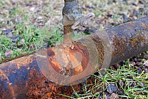 Rusty water pipe with leaking tap, closeup