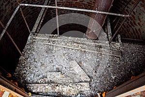 Rusty water tower inside view from top to bottom. Old water pump. Ladder to water tank, pigeon droppings