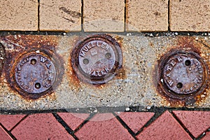 Rusty Water Utility Covers on Textured Urban Pavement