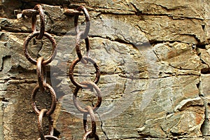 Rusty weathered iron chains shackled to rocks