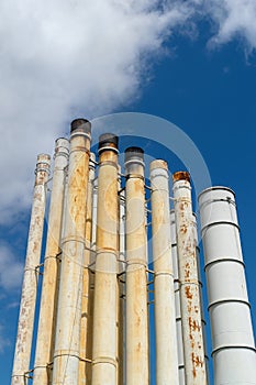 Rusty weatherworn old smokestacks against cloudy sky