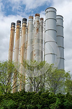 Rusty weatherworn old smokestacks against cloudy sky