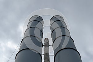 Rusty weatherworn old smokestacks against gray cloudy sky