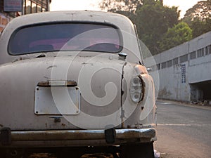 Rusty white car parked on a street of Chennai,