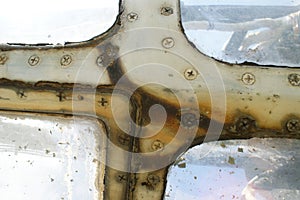 Rusty window frame of an old airplane with screws.