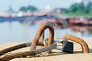 Rusty wire rope padlocked to a concrete block. Close up.