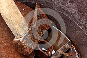 Rusty woodchopper axe, hoe and rake in rusty bucket with water