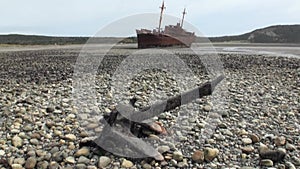 Rusty wreckage shipwreck and anchor on deserted shore beneaped dried-up ocean.