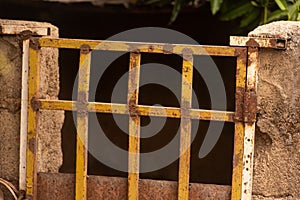 A rusty yellow steel gate and a rough cinder block wall