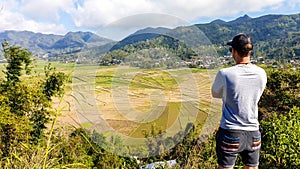 Ruteng - A man admiring spider web rice fields from above photo