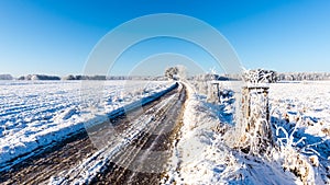 Rutted road covered by ice between snowy fields