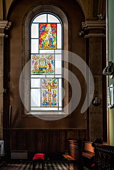 Stained glas window in church with empty seats