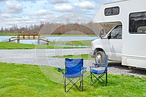 RV camper and chairs in camping, family vacation travel, holiday trip motorhome