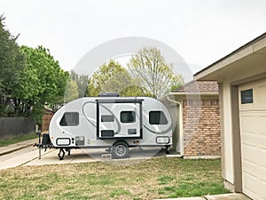 RV trailer parked at backyard of single family house, side view