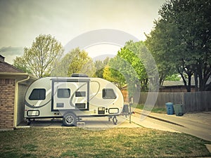 RV trailer parked at backyard of single family house, side view