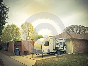 RV trailer parked at backyard of single family house, side view