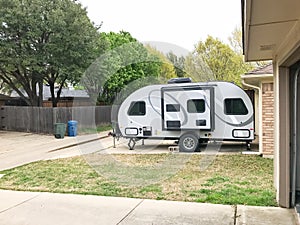 RV trailer parked at backyard of single family house, side view