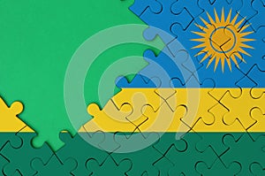 Rwanda flag is depicted on a completed jigsaw puzzle with free green copy space on the left side