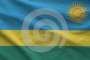 Rwanda flag depicted on folded wavy fabric of old cloth photo