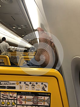 04/11/2019 - Ryanair flight from Warsaw in Poland to Amman in Jordan - Passenger resting his feet on the wall inside the aeroplane