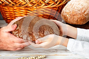 Rye black bread in his hands. A child gives a loaf to a man