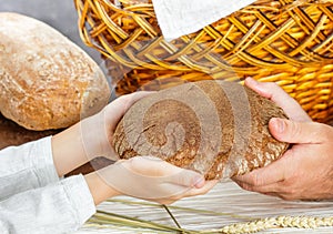 Rye black bread in his hands. A child gives a loaf to a man