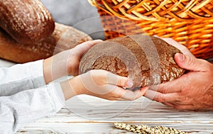 Rye black bread in his hands. A child gives a loaf to a man