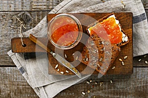 Rye bread and apricot jam sandwich on cutting board