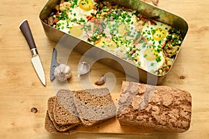 Rye bread, baked mixed vegetables and eggs close view, baking tray with tomatoes, broccoli and spices, home cooking