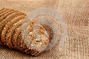 Rye bread with grains of cereals on a wooden stand on a wooden background with space for text
