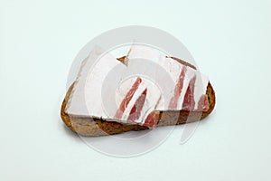 Rye bread sandwich with two pieces of bacon on a white background