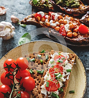Rye bread toasts with goat cheese, tomatoes, seedlings on plate on blue background with baked sweet potato toast