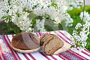 Rye bread on a wooden board against a background of with blooming cherry branches. fresh bread on a background of flowering trees