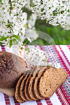 Rye bread on a wooden board against a background of with blooming cherry branches. fresh bread on a background of flowering trees