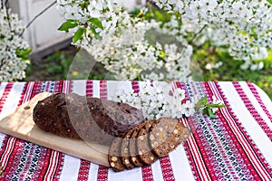 Rye bread on a wooden board against a background of with blooming cherry branches. fresh bread on a background of flowering trees