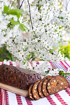 Rye bread on a wooden board against a background of with blooming cherry branches. fresh bread on a background of flowering trees