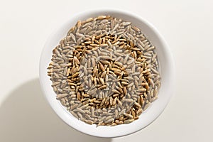 Rye cereal grain. Top view of grains in a bowl. White background