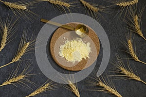 Rye flour on a board, ears of rye on a dark background. Home production concept. Top view