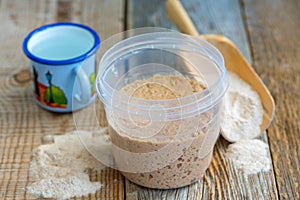 Rye sourdough, flour and a cup.